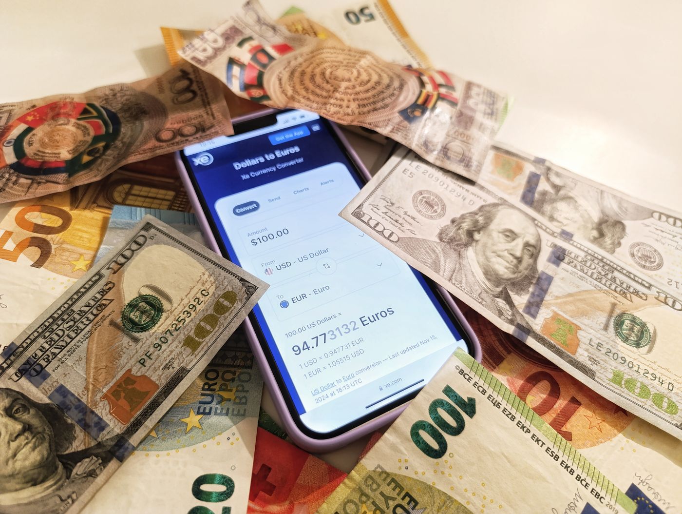 Smartphone currency converter surrounded by dollar and euro banknotes