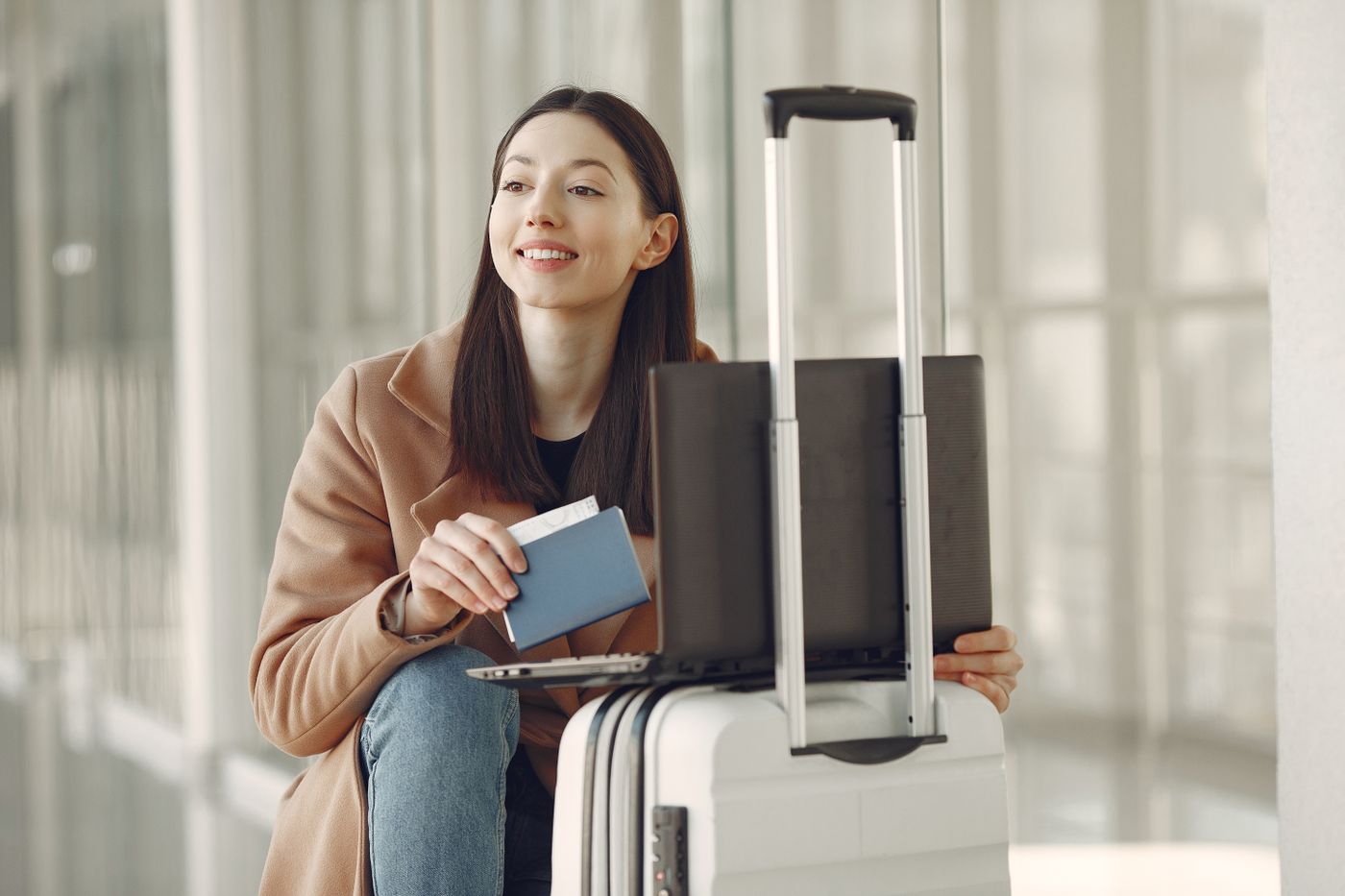Smiling traveler with passport and laptop at the airport